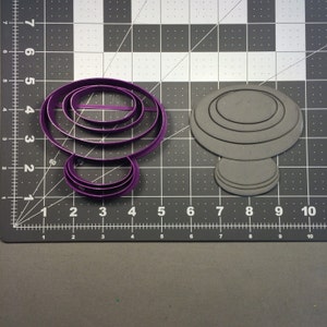 Könnte beinhalten: Zwei violette Plastik-Ausstecher, einer in Pilzform und der andere in Form eines Rings mit mehreren Schichten.