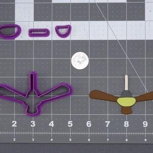 May include: A set of four cookie cutters, including a ceiling fan, a hummingbird, and two smaller shapes. The cookie cutters are purple and brown.