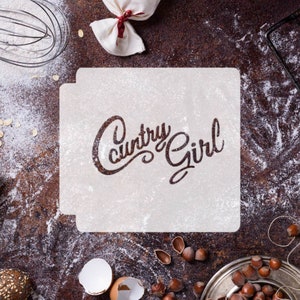May include: White stencil with the words "Country Girl" written in a cursive font. The stencil is on a brown surface with flour scattered around it.
