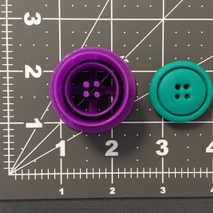 Peut inclure: Emporte-pièces en plastique violet et turquoise en forme de boutons. L'emporte-pièce violet a quatre trous au centre et l'emporte-pièce turquoise a quatre trous au centre.