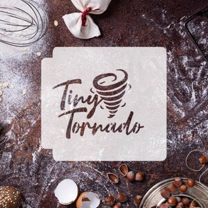 May include: A white stencil with the words "Tiny Tornado" and a stylized image of a tornado. The stencil is on a brown surface with flour scattered around it.