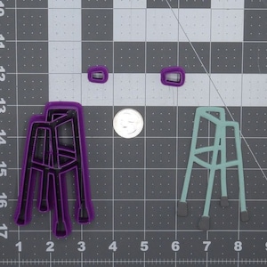 May include: Two cookie cutters in the shape of a walking frame, one purple and one teal, on a grey grid background.