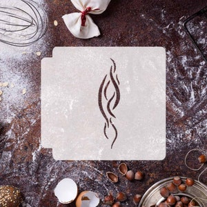 May include: White plastic stencil with a brown abstract design. The stencil is on a brown surface with flour and other baking ingredients.