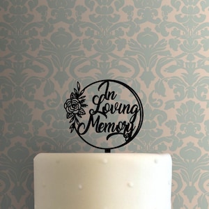 Pode incluir: Topo de bolo de acrílico preto com o texto "In Loving Memory" em um círculo com um design floral.