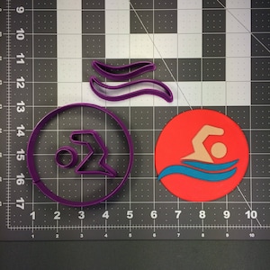 May include: Purple plastic cookie cutters in the shape of a swimmer, waves, and a circle. The swimmer is in a red circle with blue waves.
