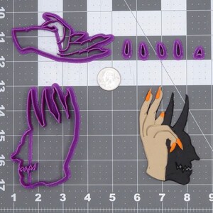May include: Three purple plastic cookie cutters shaped like hands. One hand is making a peace sign, one hand is making a fist, and one hand is making a devil's horns gesture. The devil's horns hand is also half black and half skin tone.