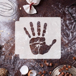May include: A white stencil with a handprint design on a brown surface with flour and other baking ingredients.
