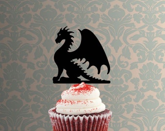 May include: Black silhouette of a dragon cupcake topper on a red velvet cupcake with white frosting.