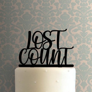 May include: Black acrylic cake topper with the words "Lost Count" in a cursive font.