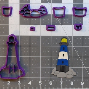 May include: Purple plastic cookie cutters in the shape of a lighthouse, rocks, and a bucket. The lighthouse has a white and blue striped tower and a yellow light on top.