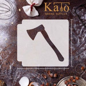 Könnte beinhalten: Eine weiße Schablone mit der Silhouette einer Axt auf braunem Hintergrund. Die Schablone ist 12,7 cm breit und 10,2 cm hoch. Die Schablone ist mit "Kato Baking Supplies" beschriftet.