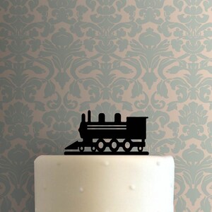Op de afbeelding: Zwarte silhouet van een locomotieftaarttopper. De locomotief heeft een afgeronde voorkant, een rechthoekig lichaam en vier wielen.