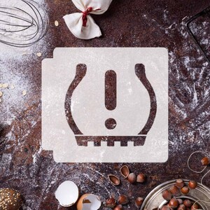 May include: White stencil of a tire pressure warning symbol on a brown surface covered in flour. The symbol is a tire with an exclamation point inside.