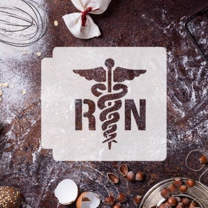 May include: A white stencil featuring the medical symbol of a snake entwined around a staff, along with the letters RN. The stencil is positioned on a brown surface with flour scattered around it.