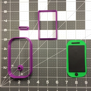 Puede incluir: Tres cortadores de galletas de plástico morado con forma de teléfono inteligente, pantalla de teléfono inteligente y botón de teléfono inteligente. Los cortadores están sobre un fondo de cuadrícula gris.
