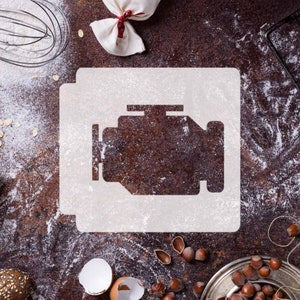 May include: A white stencil of a car engine check light symbol on a brown, rustic surface covered in white flour. The surface is also decorated with hazelnuts, a broken eggshell, and a white cloth bag.