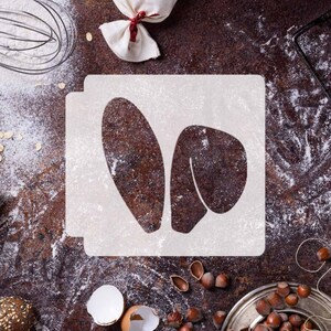 May include: White stencil with a bunny rabbit silhouette on a brown background with flour and baking supplies.