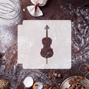May include: A white stencil of a cello silhouette on a brown, rustic surface with flour scattered around it. There are also other baking supplies, such as a whisk, nuts, and an egg shell.