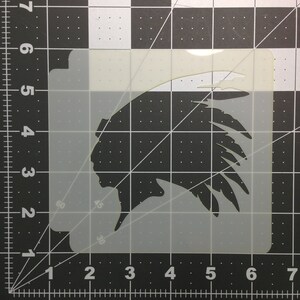 May include: A white plastic stencil of a Native American chief wearing a headdress. The stencil is on a black and white grid background.
