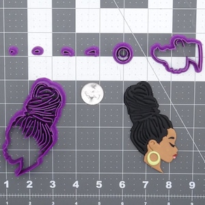 Peut inclure: Emporte-pièces en plastique violet en forme de femme avec une coiffure en chignon, un petit chignon et un cercle. La femme porte une grande boucle d'oreille.