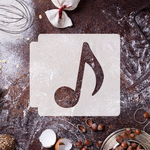 May include: A white stencil with a musical note shape on a brown surface covered in white flour. There are other baking supplies in the background.