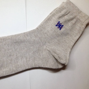 May include: A pair of gray socks with a small blue embroidered logo. The socks are made with Ukrainian raw materials, as indicated by the yellow label attached to the sock.