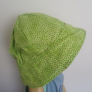 K&ouml;nnte beinhalten: Ein gr&uuml;ner Sonnenhut mit wei&szlig;em Hintergrund und kleinen gr&uuml;nen Punkten.