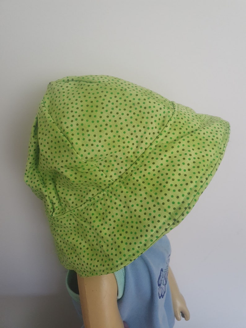 K&ouml;nnte beinhalten: Ein gr&uuml;ner Sonnenhut mit wei&szlig;em Hintergrund und kleinen gr&uuml;nen Punkten.