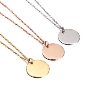 May include: Three gold, rose gold, and silver necklaces with round pendant charms. The necklaces are on a white background.