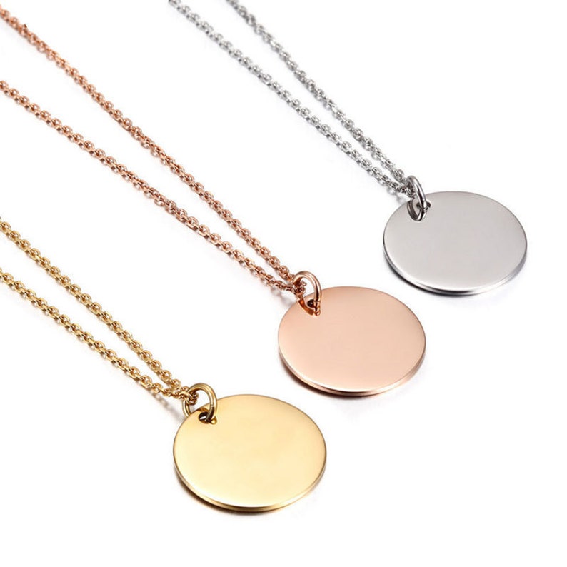 May include: Three gold, rose gold, and silver necklaces with round pendant charms. The necklaces are on a white background.