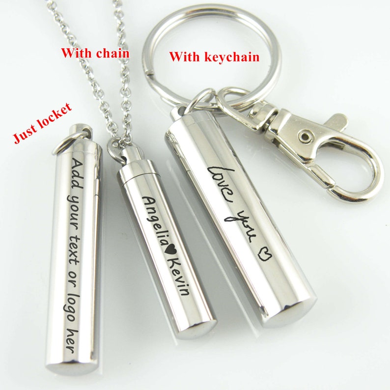 May include: Three silver metal cylindrical lockets with different engravings. The locket on the left says "Add your text or logo here". The middle locket says "Angelia Kevin" with a small heart symbol. The locket on the right says "Love you" with a heart symbol. The lockets are shown with a chain and a keychain.