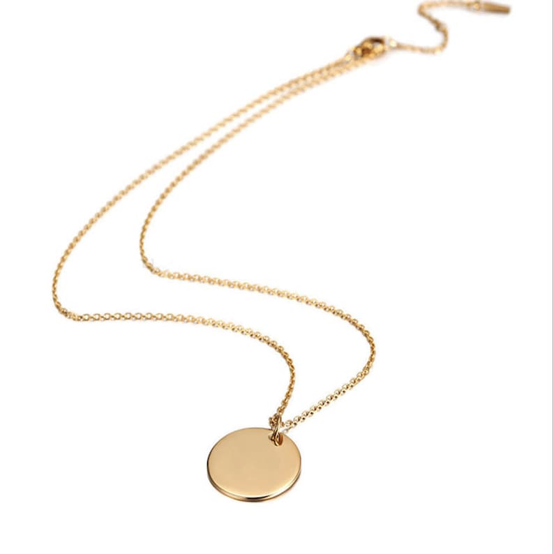 May include: A gold chain necklace with a round, plain gold pendant.