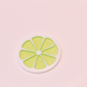 May include: A white and green lime slice charm with a glittery finish.