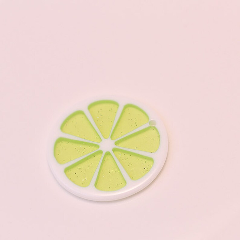 May include: A white and green lime slice charm with a glittery finish.