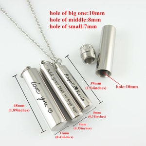 May include: Three silver cylindrical cremation urns with a chain and a silver pendant. The urns are engraved with the text "Love you", "Add your text or logo here", and "Angelia Kevin". The urns are 1.89 inches, 0.43 inches, and 1.54 inches in length.