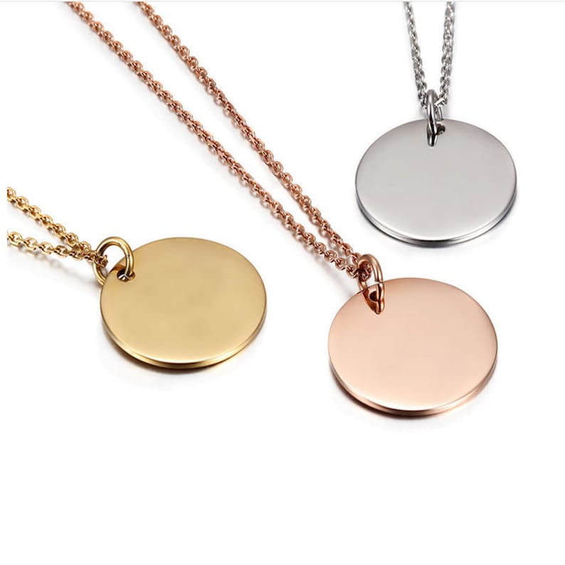 May include: Three silver necklaces with round, blank pendants. The pendants are silver, gold, and rose gold.