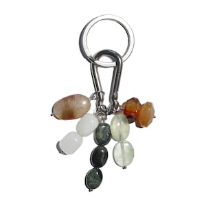 May include: A keyring with a silver ring and clasp, featuring a cluster of colourful gemstones. The stones include oval-shaped beads in shades of brown, white, green, and orange. The keyring is designed for holding keys.
