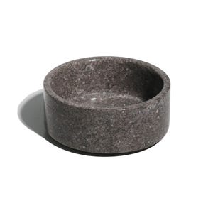 Può includere: Una piccola ciotola rotonda in marmo grigio con un motivo maculato. La ciotola è vuota e ha una superficie liscia e lucida.