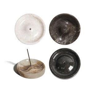 May include: Four round marble incense holders in different colors and patterns. The holders have a small hole in the center for incense sticks.