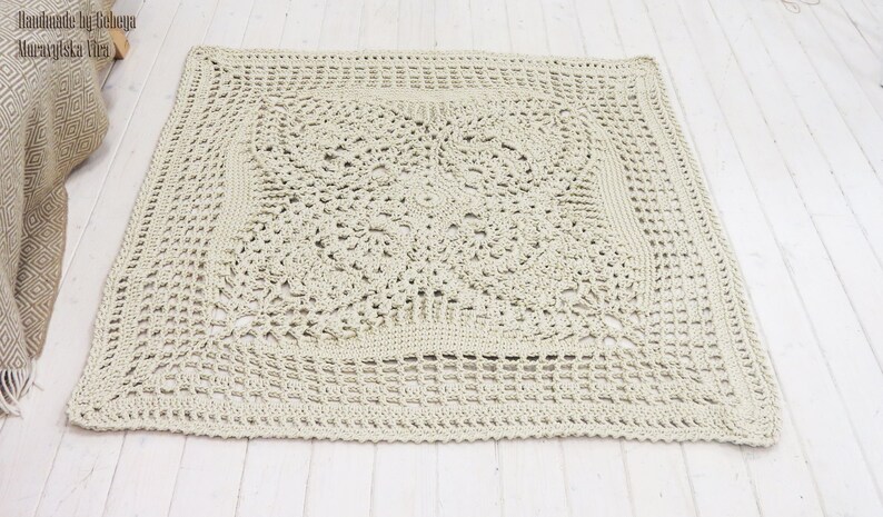 May include: A large, square, crocheted throw blanket in a light beige color. The blanket has a delicate, intricate pattern with a central square motif.