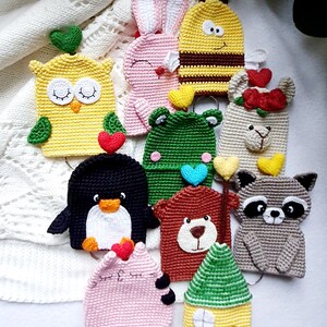 May include: A collection of 10 crocheted animal keychains, including a yellow owl, pink bunny, yellow bee, white llama, green frog, black penguin, brown bear, grey raccoon, pink cat, and a yellow house with a green roof.