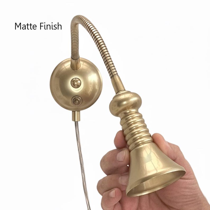 May include: A matte finish brass-colored wall-mounted reading lamp. The lamp features a flexible gooseneck arm and a bell-shaped head. The text "Matte Finish" is visible in the image.