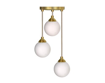 White Globe Shades on Silicon Transparent Cords. Solid Brass in a Gold/Brass Finish. 3 Glass Globe White Shades.