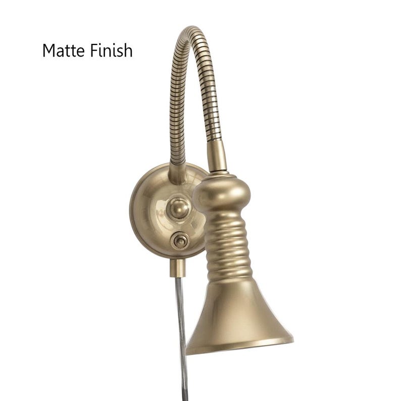 May include: A matte finish, brass-colored wall-mounted reading lamp. The lamp features a flexible gooseneck arm and a conical shade. The text "Matte Finish" is visible in the image. The lamp is designed for focused lighting.