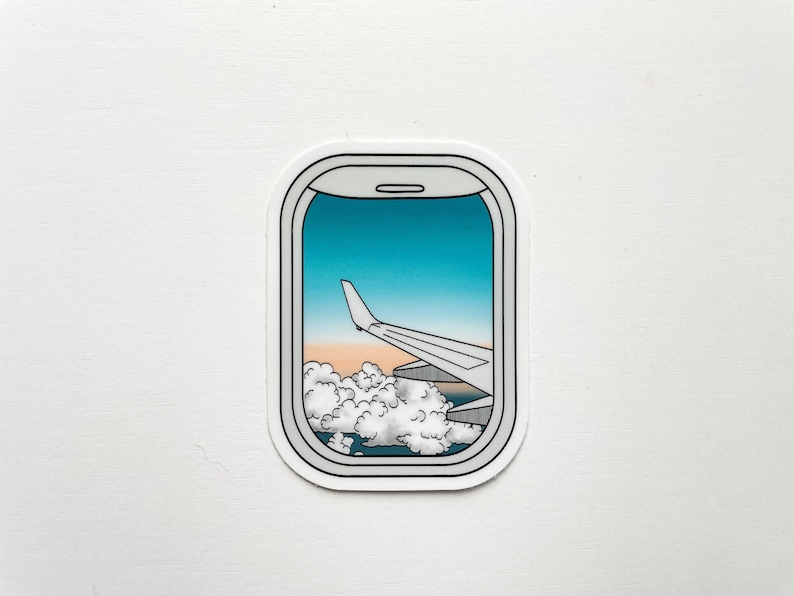 May include: A sticker of an airplane window view with a wing and clouds in the distance. The sky is blue with a sunset in the background.