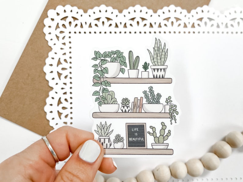 May include: A white sticker with a hand-drawn illustration of a shelf with potted plants and the text "Life is Beautiful" on a chalkboard.