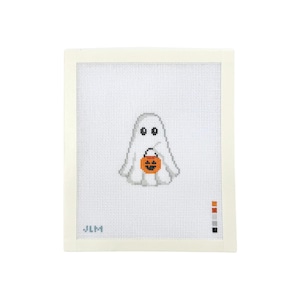 May include: A white needlepoint canvas featuring a centered ghost design with black eyes and a small orange jack-o'-lantern bucket. The canvas includes a color palette guide in the bottom right corner and the letters JLM in the bottom left corner.