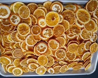 May include: A tray filled with numerous dried orange slices. The slices vary in size and shape, showcasing a range of natural textures and colors from light yellow to deep orange. The arrangement suggests a culinary or decorative theme.