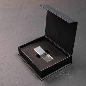 May include: A silver and clear crystal USB drive in a black gift box. The box is open and the drive is sitting in the center of the box.
