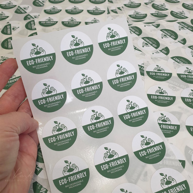 May include: A sheet of round, white stickers with green text that reads "ECO-FRIENDLY BIO-DEGRADABLE PACKAGING". The stickers are arranged in rows and columns on a white background.